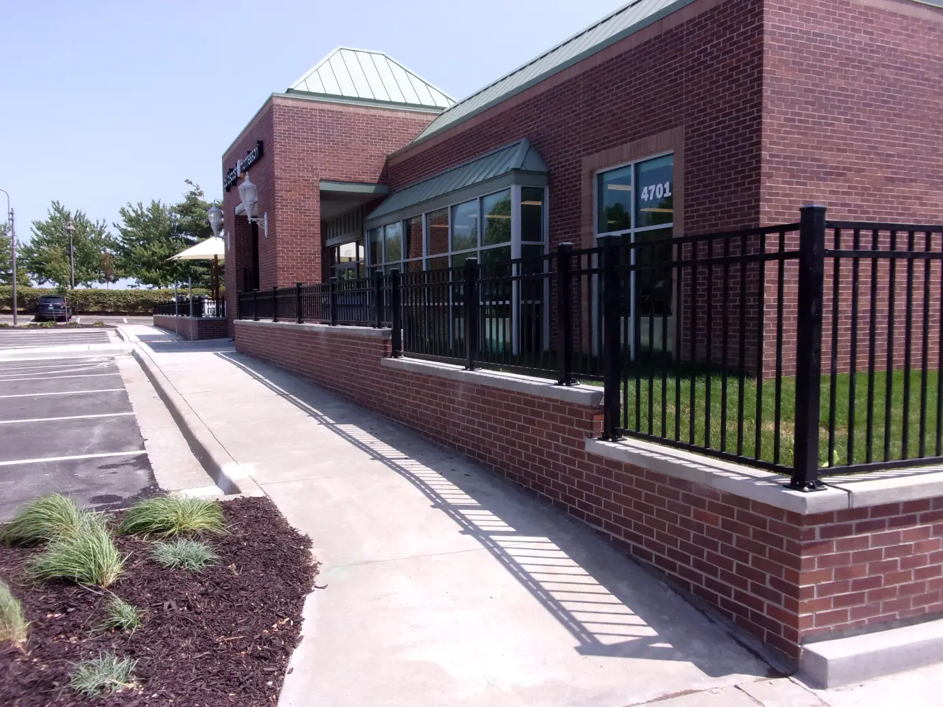 Black metal fence mounted on top of a brick wall that is surrounding a new daycare building that was just built. 