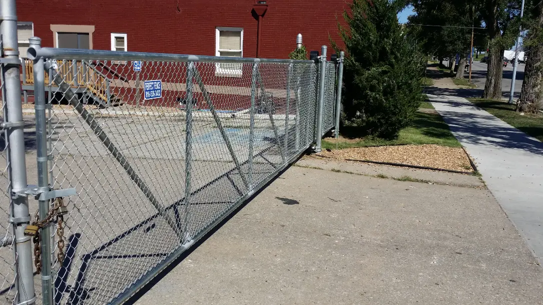 Metal frame cantilever gate with chain link attached to the frame that spans a twenty five foot wide driveway into a parking lot downtown.