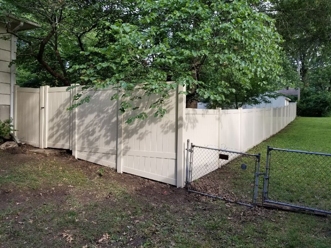 A photo of a white vinyl privacy fence enclosing a residential yard